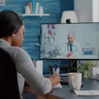 African american woman writing respiratory sickness treatment on notebook discussing pills treatment during online healthcare videocall meeting conference. Therapist doctor working remote from home